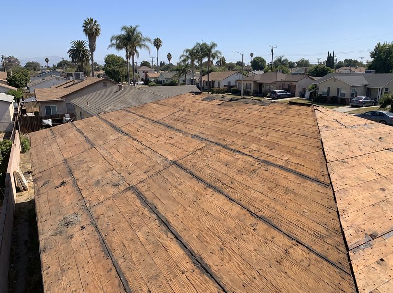 A roof stripped back to bare plywood decking during a tear-off