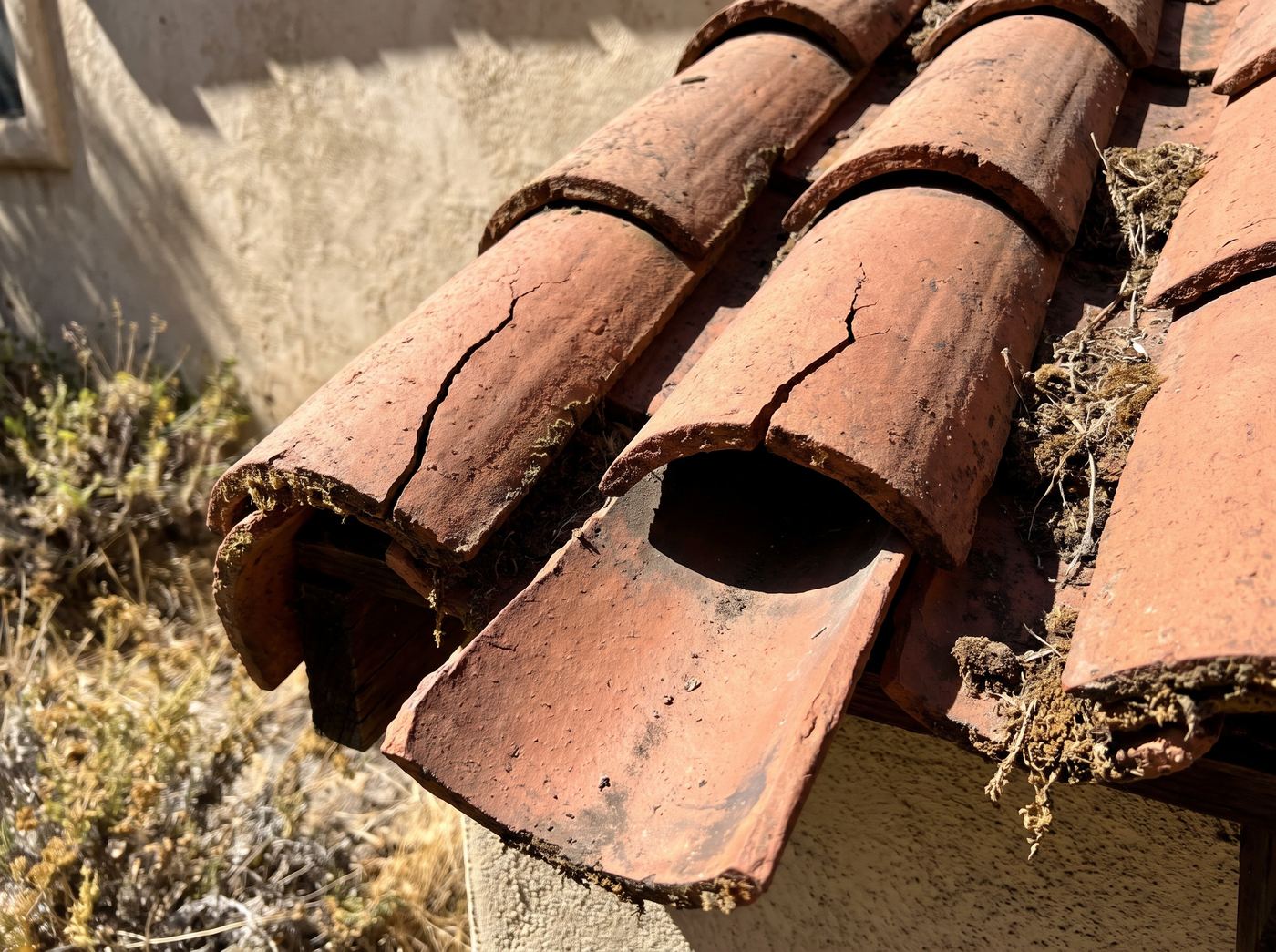 Cracked terracotta barrel tiles with one slipped out of alignment